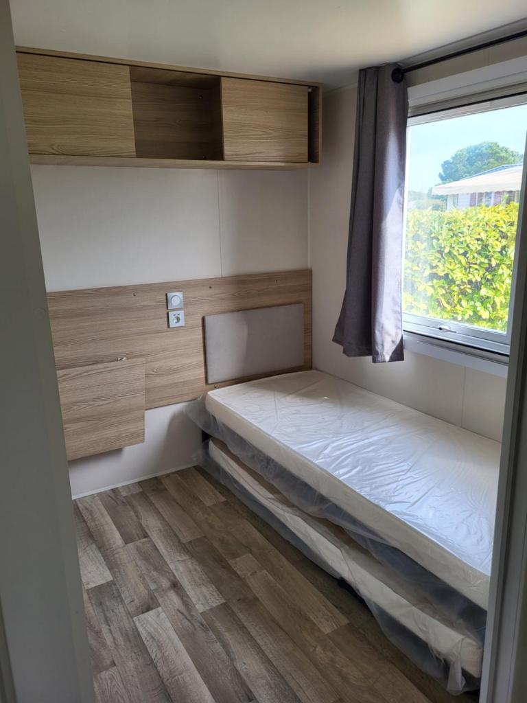 une petite chambre avec un lit et une fenêtre dans l'établissement Mobil-home à Lattes, à Lattes