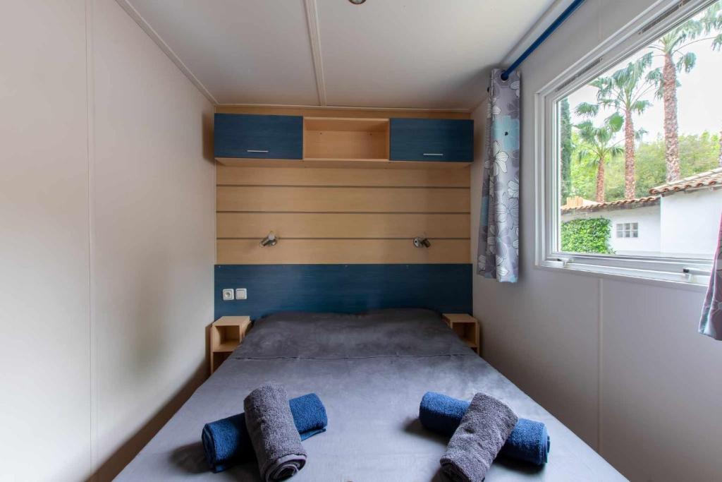 - un petit lit dans une petite chambre avec fenêtre dans l'établissement Mobil-home Entre Terre & Mer, à Agde