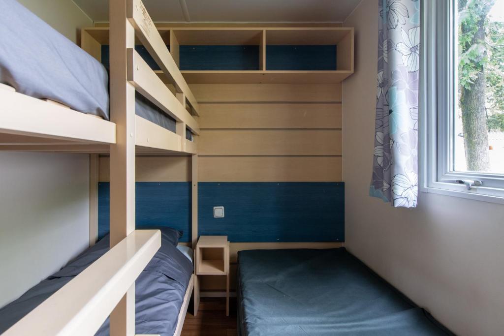 Cette petite chambre comprend des lits superposés et une fenêtre. dans l'établissement Mobil-home Entre Terre & Mer, à Agde