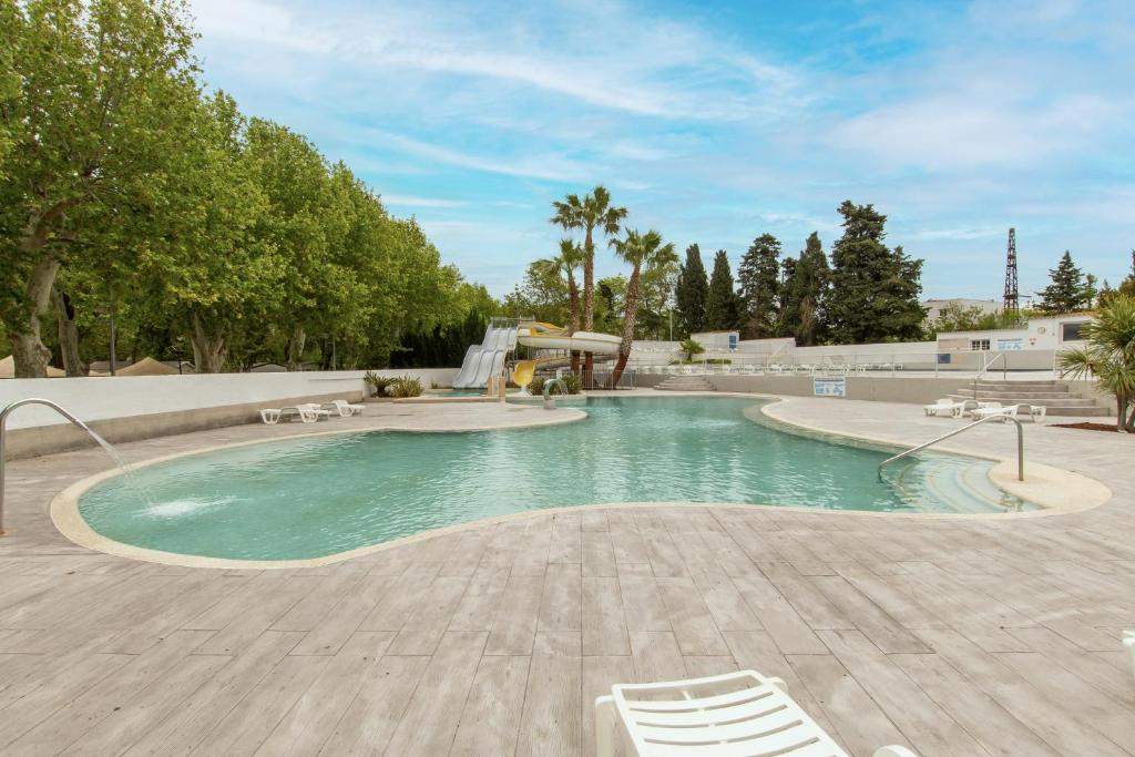 - une piscine avec 2 chaises et une cascade dans l'établissement Mobil-home Entre Terre & Mer, à Agde