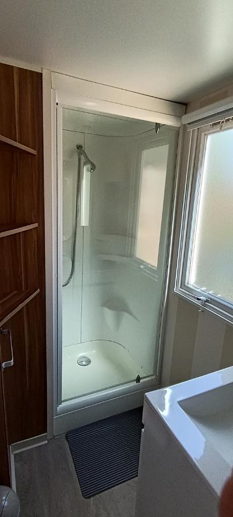 une salle de bain avec une douche avec une porte vitrée dans l'établissement Mobil home 6 personnes confort Océan climatisé camping avec piscine Agde, à Agde 8 autres photos