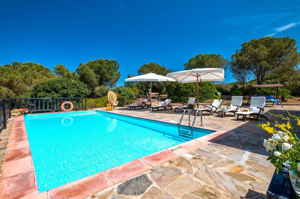 une piscine avec chaises et parasols dans une cour dans l'établissement Alghero Villa Barranch with sea view swimming pool for 6 people, à Alghero