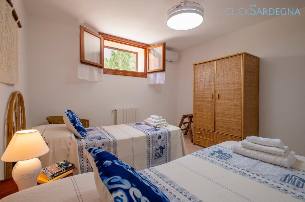 - une chambre avec 2 lits, une fenêtre et une armoire dans l'établissement Alghero Villa Barranch with sea view swimming pool for 6 people, à Alghero