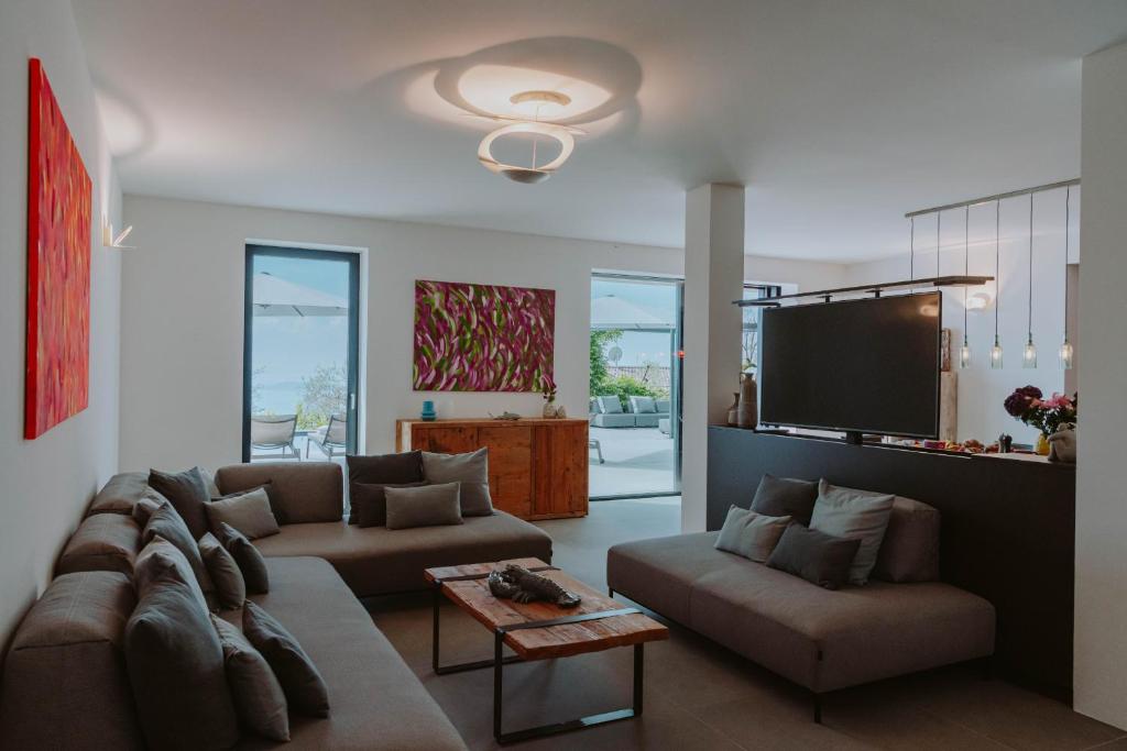 un salon avec deux canapés et une télévision à écran plat dans l'établissement Villa Dolce Vista, à Gardone Riviera