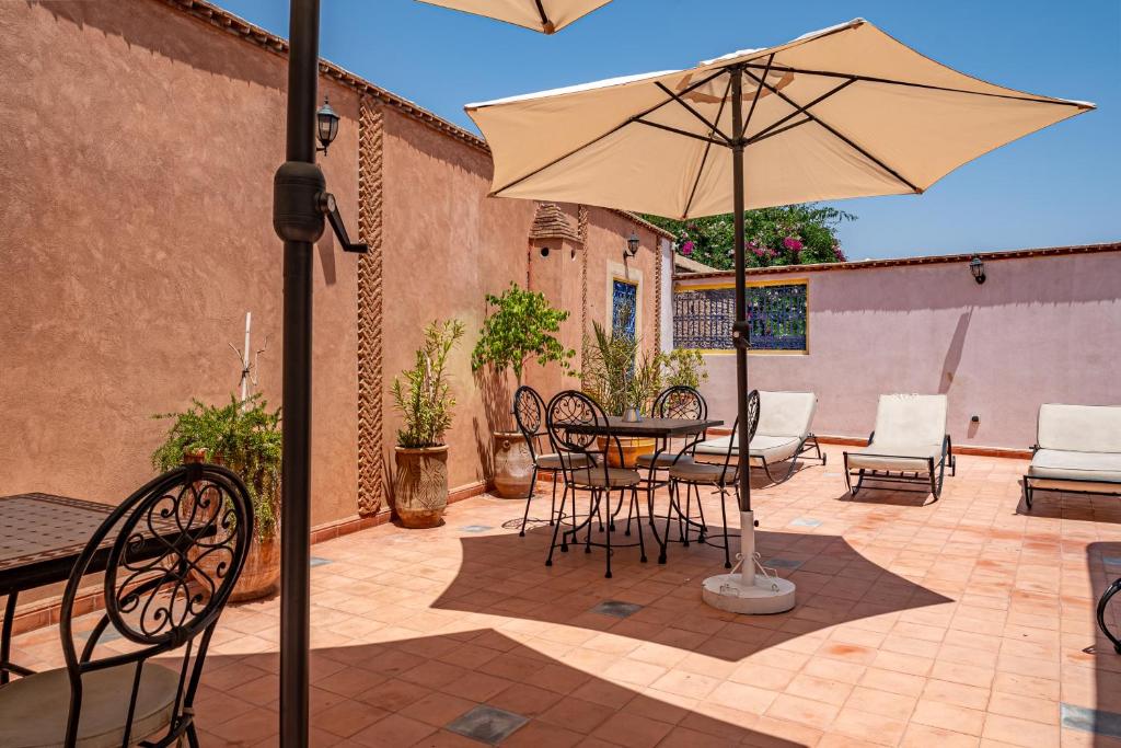 un patio avec une table, des chaises et un parasol dans l'établissement RIAD VILLA SIDI BABA, à Marrakech