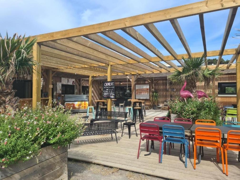 une terrasse en bois avec des chaises colorées et une table. dans l'établissement Charmant mobil-home 98, à Narbonne
