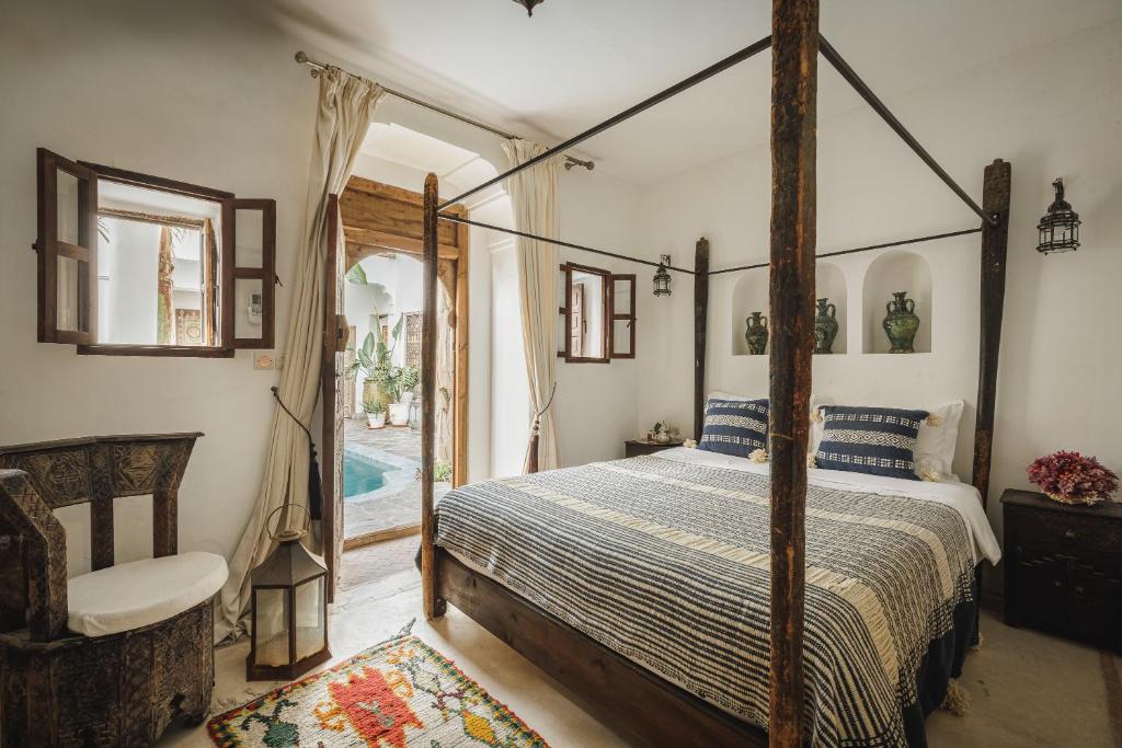 - une chambre avec un lit à baldaquin et une piscine dans l'établissement Riad Alkemia en exclusivité, à Marrakech
