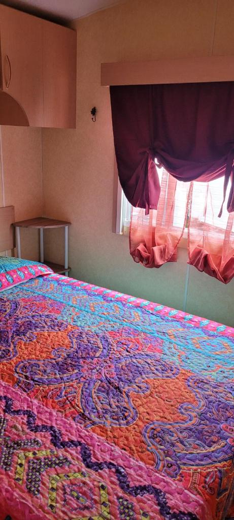 - un lit avec une couverture colorée dans une chambre dans l'établissement Mobil home Camping Bleu Marine, à Sérignan