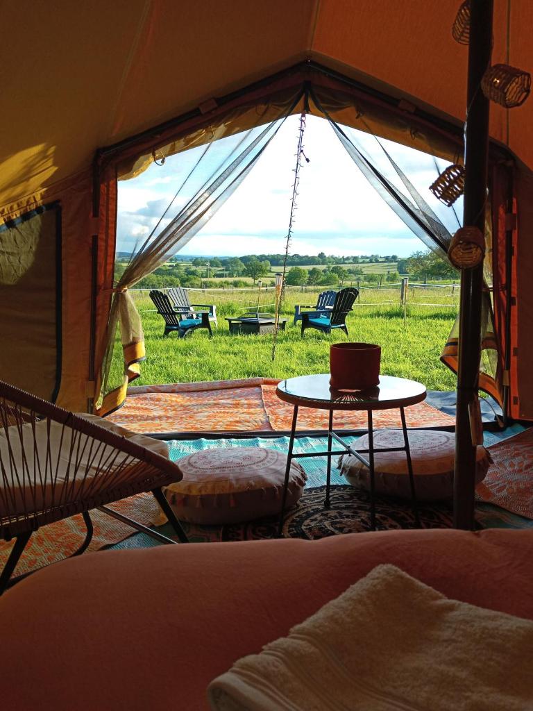 Cette chambre comprend une tente avec une table et des chaises. dans l'établissement Tente au milieu des chevaux, à Mont