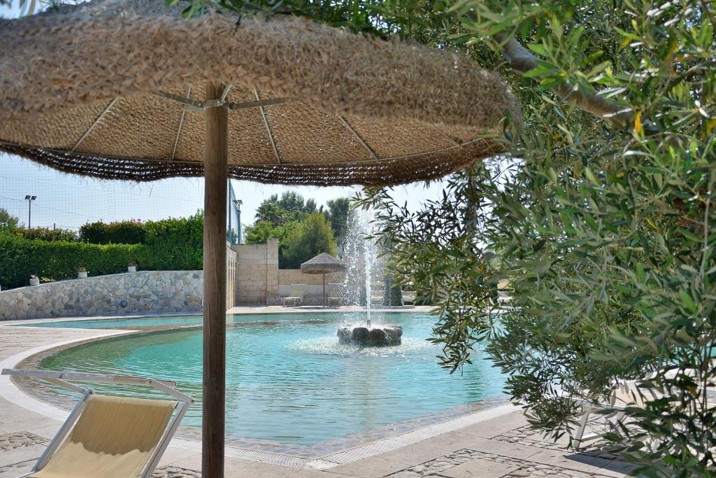 un parasol et une chaise à côté d'une fontaine dans l'établissement Hotel Thàlas Club, à Torre dell'Orso