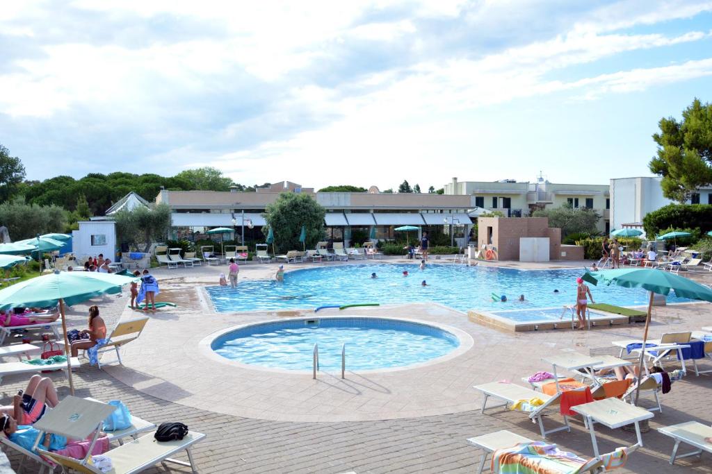une grande piscine avec des personnes assises autour de celle-ci dans l'établissement Hotel Thàlas Club, à Torre dell'Orso