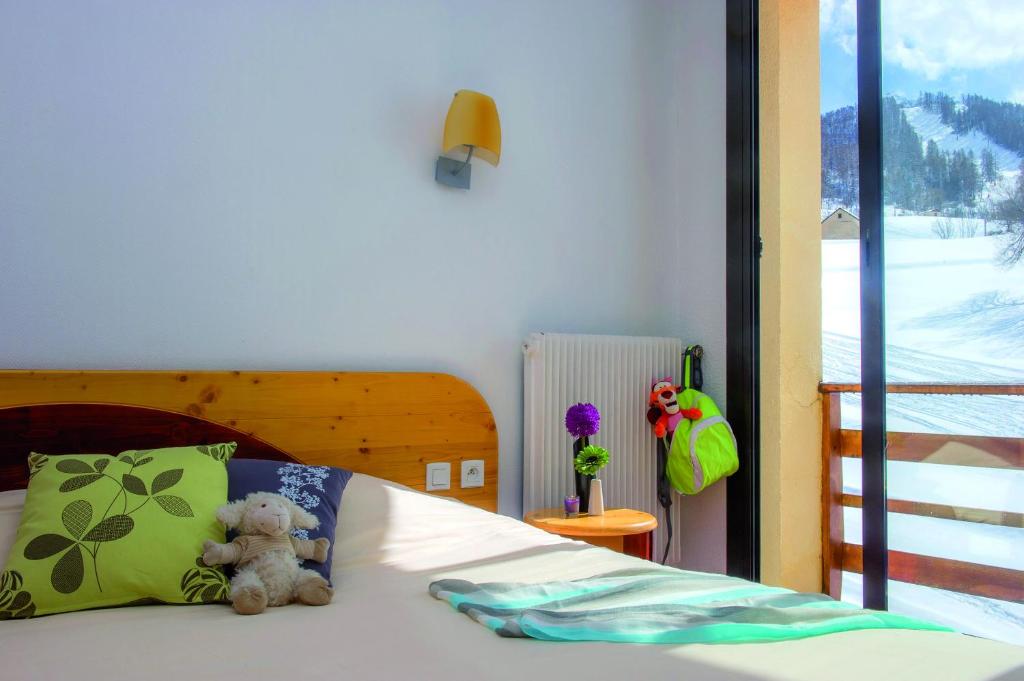 un ours en peluche assis sur un lit dans l'établissement VTF Les Balcons du Sauze, au Sauze