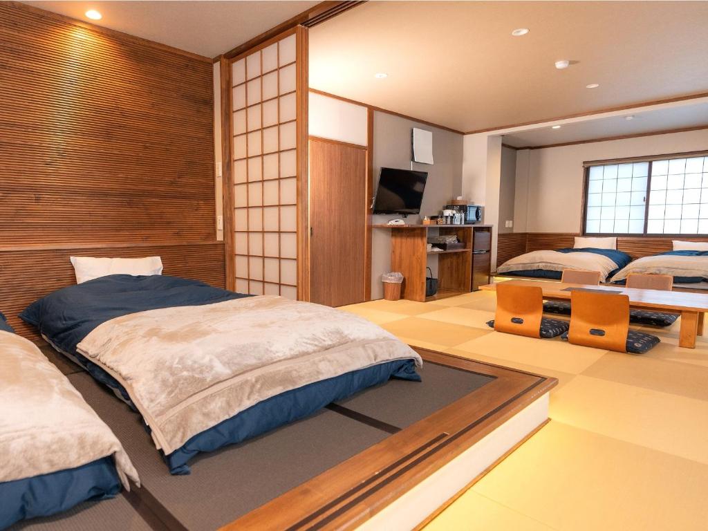 - une chambre avec 2 lits et une télévision dans l'établissement Nozawa Onsen Azegamikan, à Nozawa Onsen
