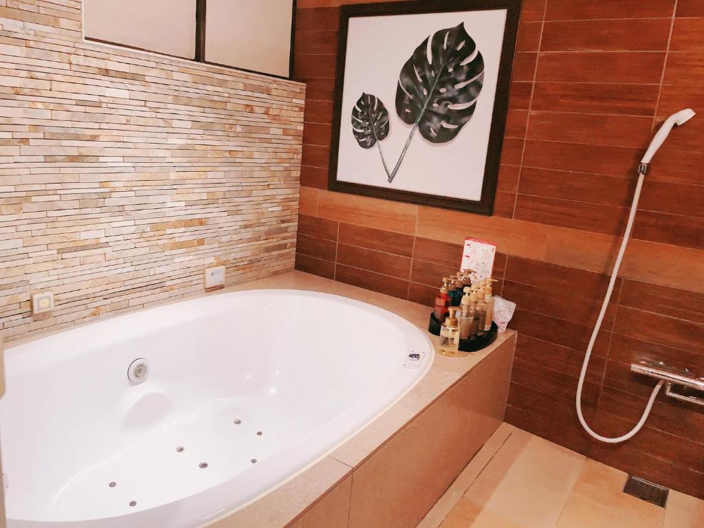 une baignoire dans une salle de bain aux murs en bois dans l'établissement HOTEL BALIS - Adult Only, à Shizukuishi