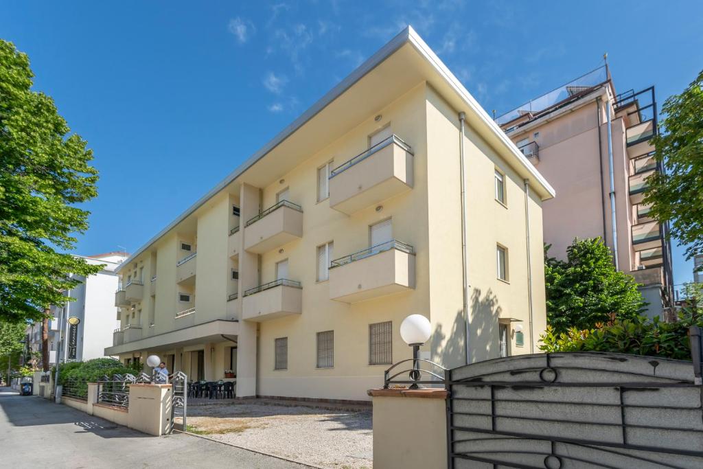 un immeuble d'appartements avec une clôture devant lui dans l'établissement Hotel Vannucci, à Rimini