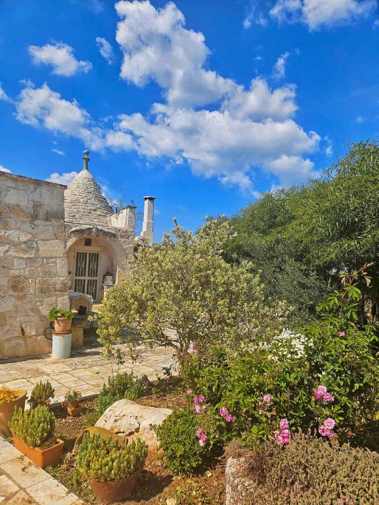 un jardin avec des fleurs et des plantes devant un bâtiment dans l'établissement Trullo di Angela - Ostuni with private pool, à Ostuni