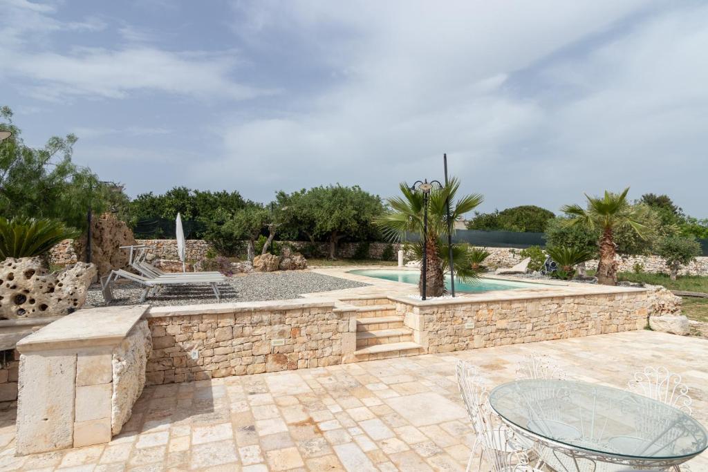 d'une terrasse avec un mur en pierre et une table. dans l'établissement Trulli San Pietro, à Putignano