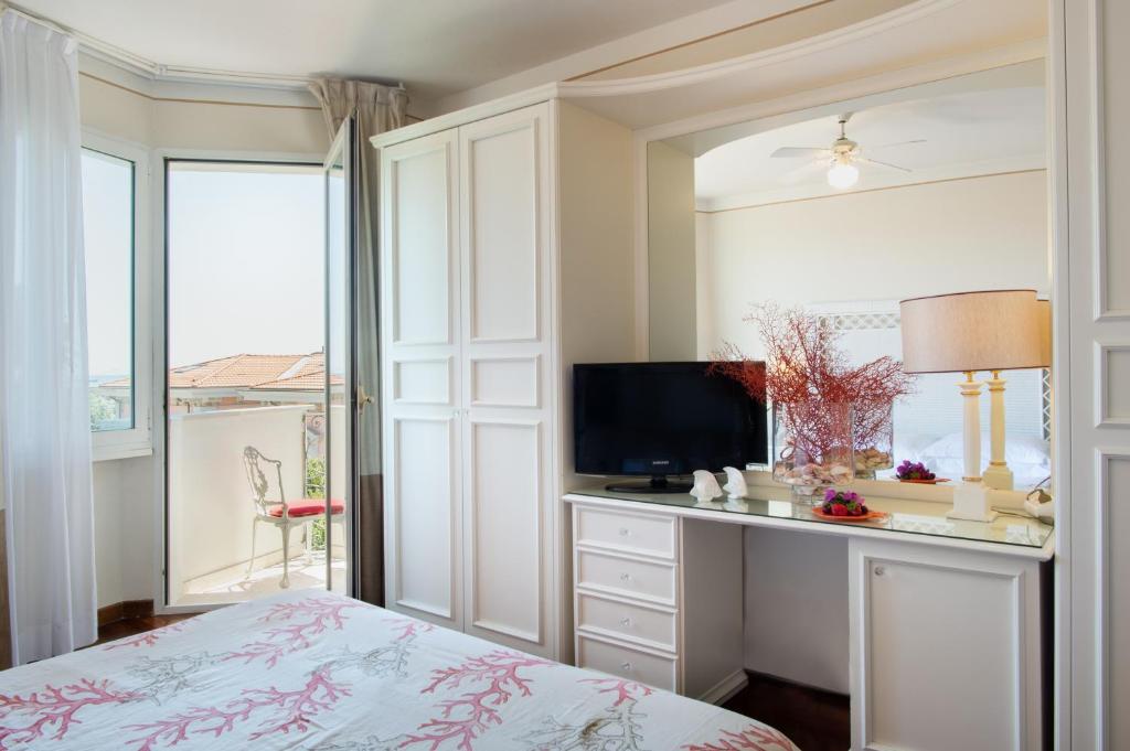 une chambre avec un lit et un bureau avec une télévision dans l'établissement Hotel Il Negresco, à Forte dei Marmi