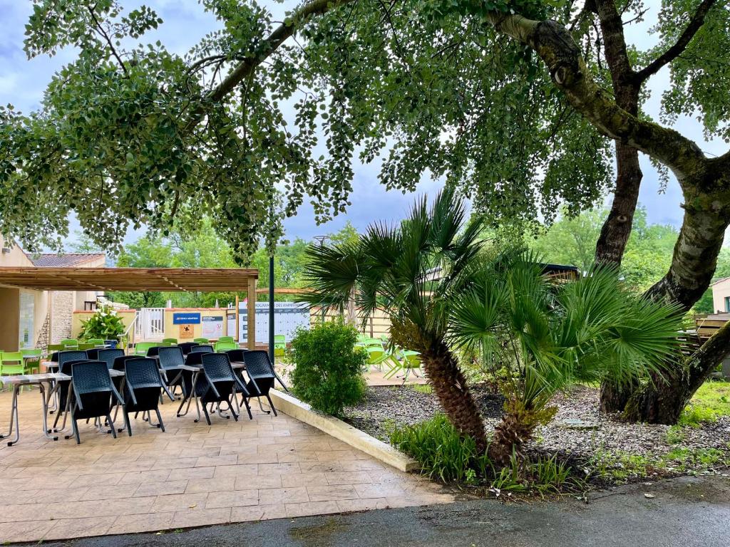 d'une terrasse avec une table, des chaises et un arbre. dans l'établissement Les jardins privés 148 Camping le Clos Cottet, à Angles
