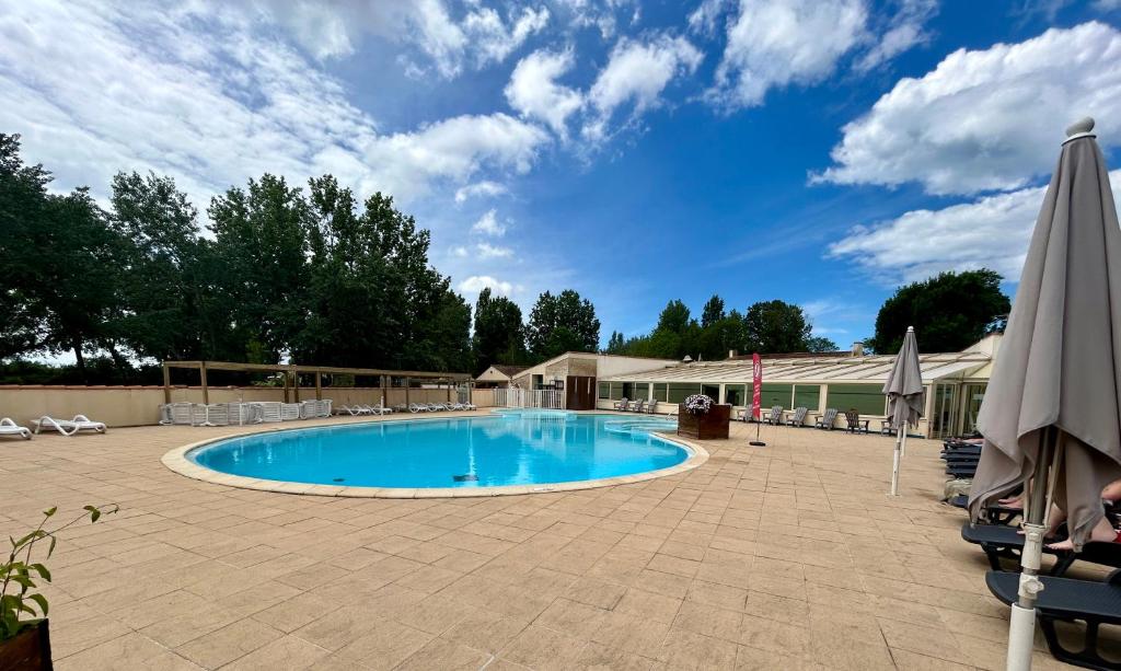 une grande piscine dans une cour avec un parasol dans l'établissement Les jardins privés 148 Camping le Clos Cottet, à Angles