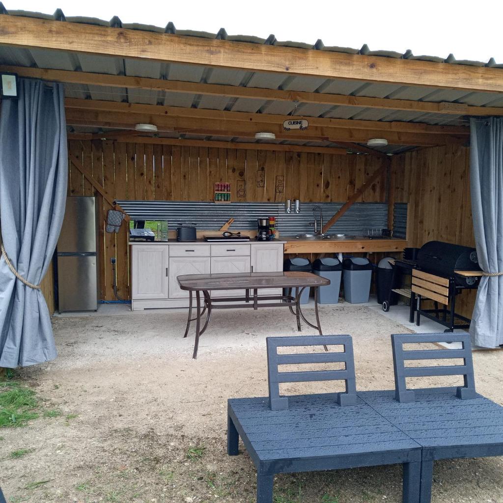 un patio avec une table et des chaises et une cuisine dans l'établissement La Clef des Songes, à Herry
