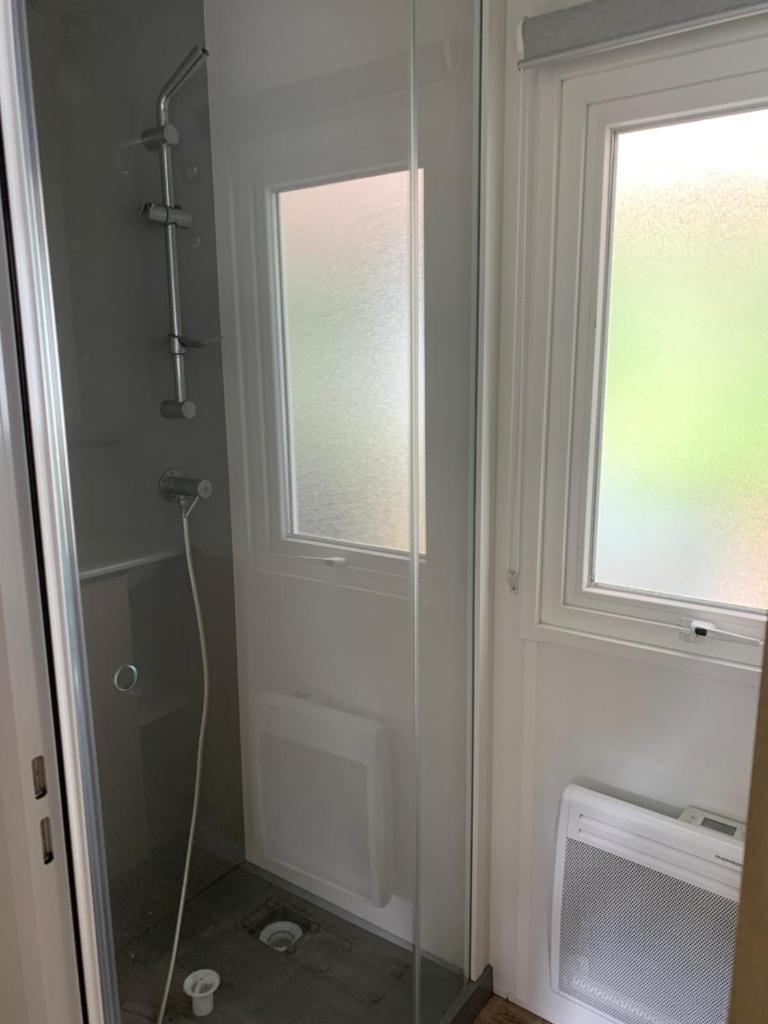 une salle de bain avec une douche avec une porte vitrée dans l'établissement MH 008 Bora Bora sur emplacement exceptionnel en lisière de forêt dans camping 4 étoiles, à Saint-Julien-en-Born 8 autres photos