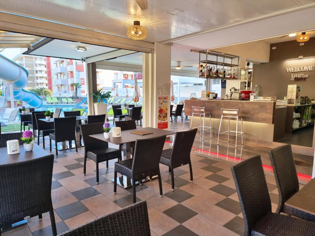 un restaurant avec des tables et des chaises et un bar dans l'établissement Hotel Alexander, à Bibione
