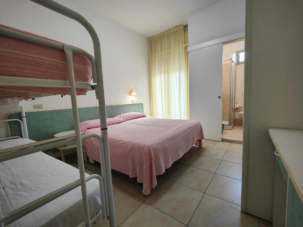 - une chambre avec des lits superposés et un couvre-lit rose dans l'établissement Hotel Ben Hur, à Cesenatico
