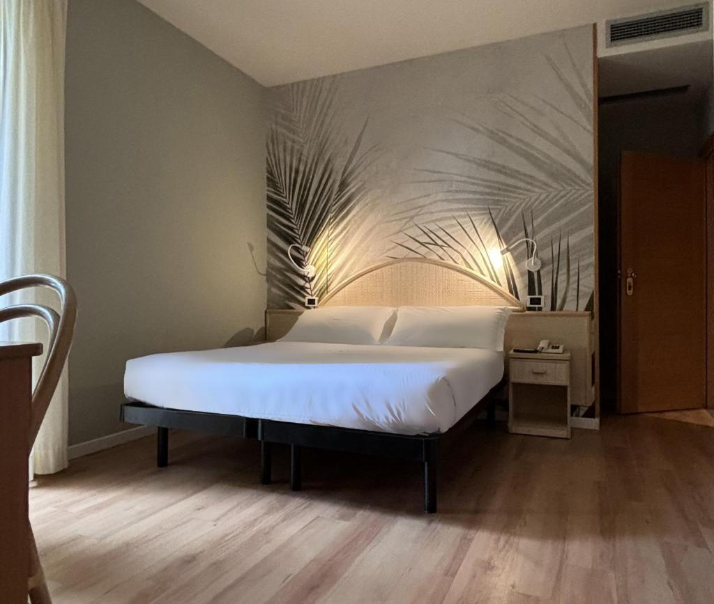 une chambre avec un grand lit avec des draps blancs dans l'établissement Pinetina Mare Baby Family Hotel, à Cervia