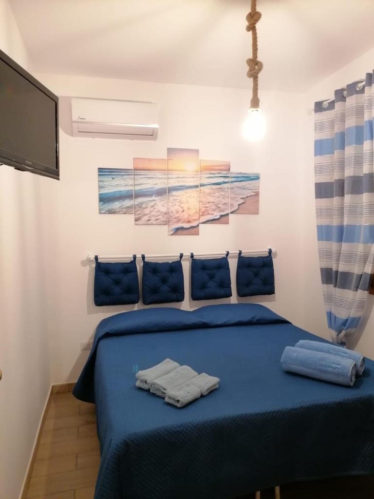 - une chambre avec un lit bleu et trois peintures murales dans l'établissement Villa Mykonos, à Fontane Bianche