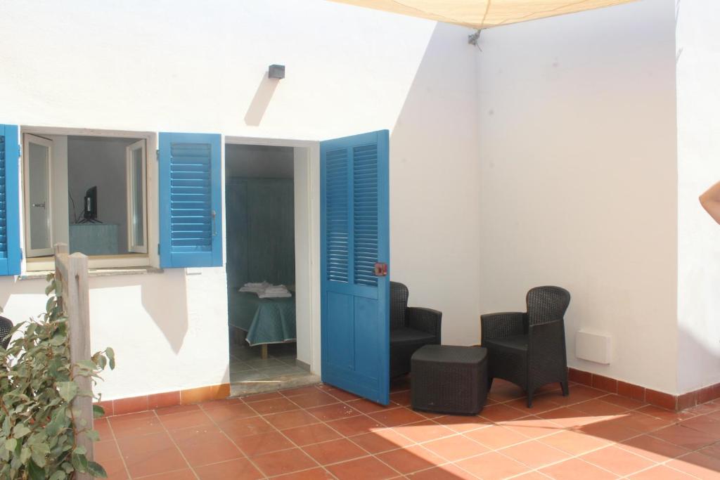 une pièce avec une porte bleue et deux chaises dans l'établissement Vel Marì - Rooms on the Beach, à Alghero