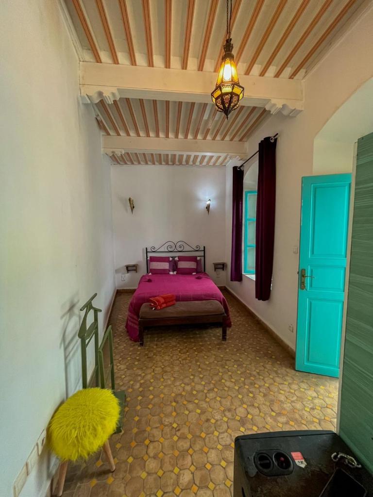 une chambre avec un lit rose et une porte bleue dans l'établissement Riad Darko, à Essaouira