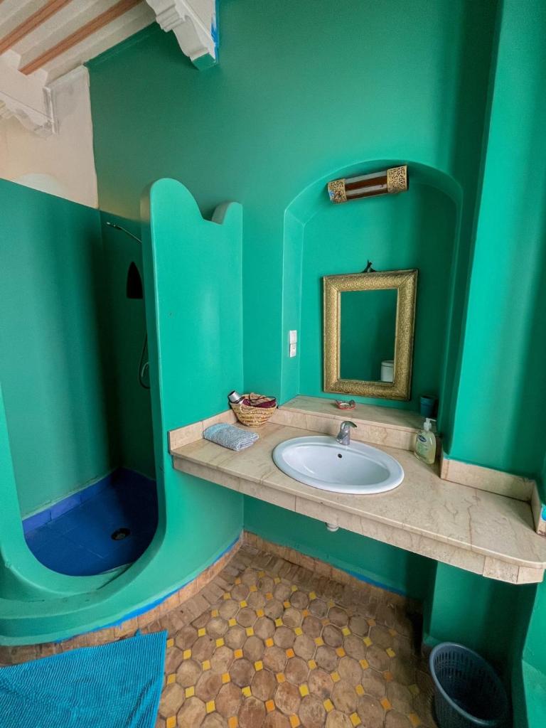 La salle de bains verte est pourvue d'un lavabo et d'un miroir. dans l'établissement Riad Darko, à Essaouira
