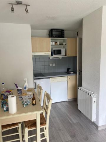 une cuisine avec une table et des chaises dans une pièce dans l'établissement Skis aux pieds station 1600 Sun Vallée, à Puy-Saint-Vincent