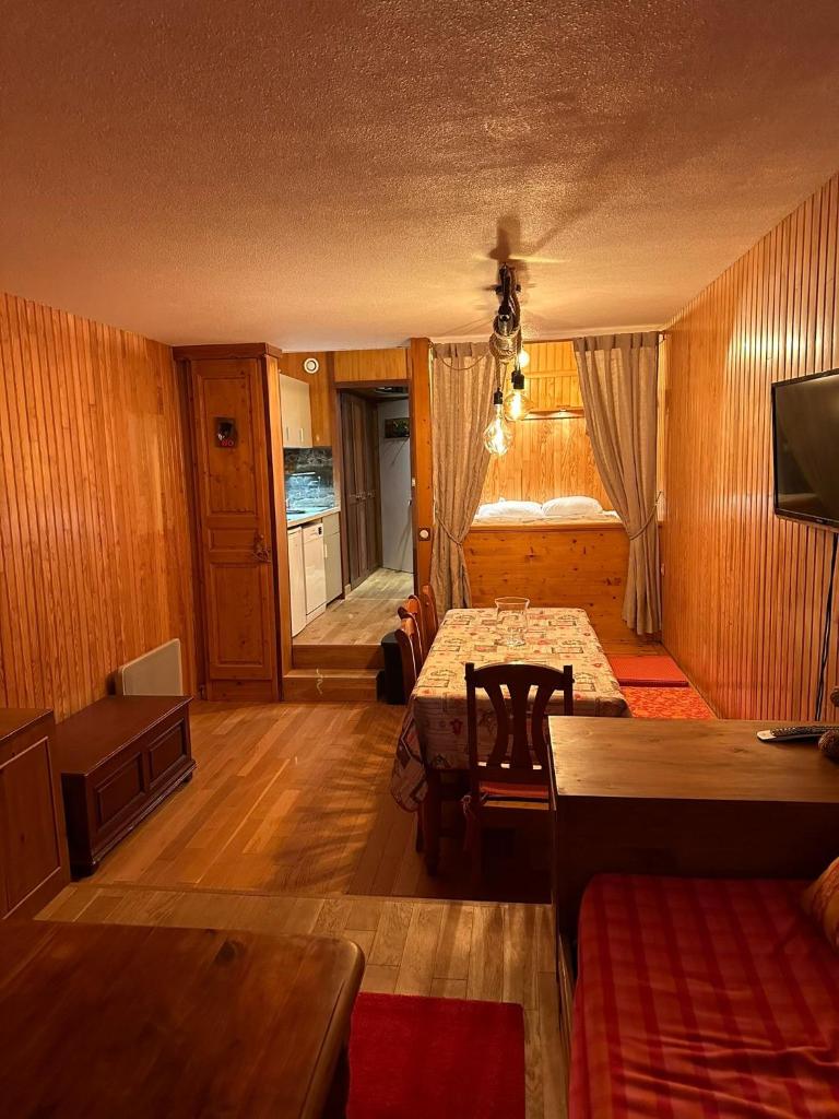 Cette chambre dispose de murs en bois, d'une table et d'un canapé. dans l'établissement Appartement Front de neige, à Isola