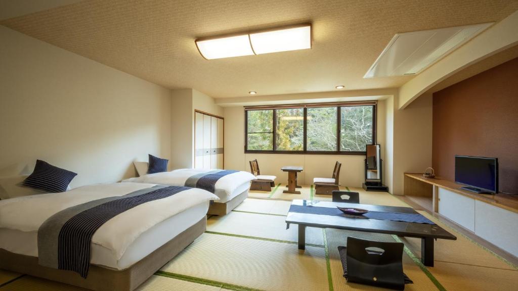une chambre d'hôtel avec deux lits et une télévision dans l'établissement Yamagataya, à Kitakata