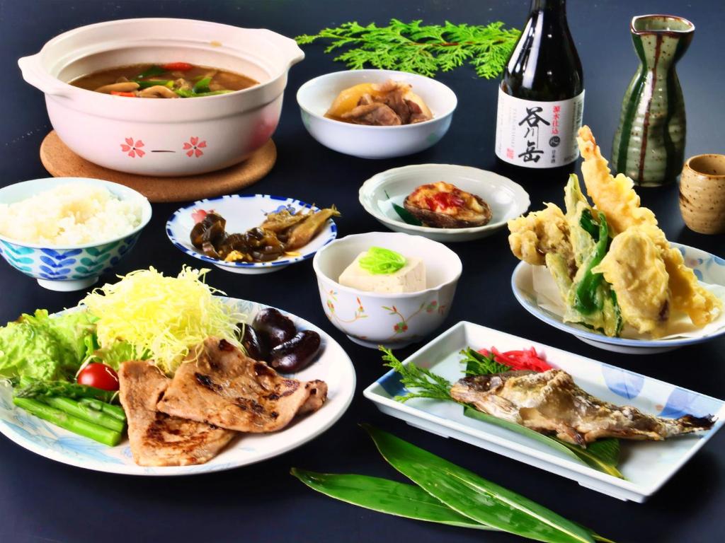 - une table avec des plats et une bouteille de vin dans l'établissement Hanasaku Onsen Yoshiyaso, à Katashina