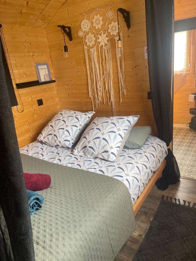 - un lit avec des oreillers dans une chambre dotée de murs en bois dans l'établissement Roulotte , hébergement atypique, à Solliès-Pont