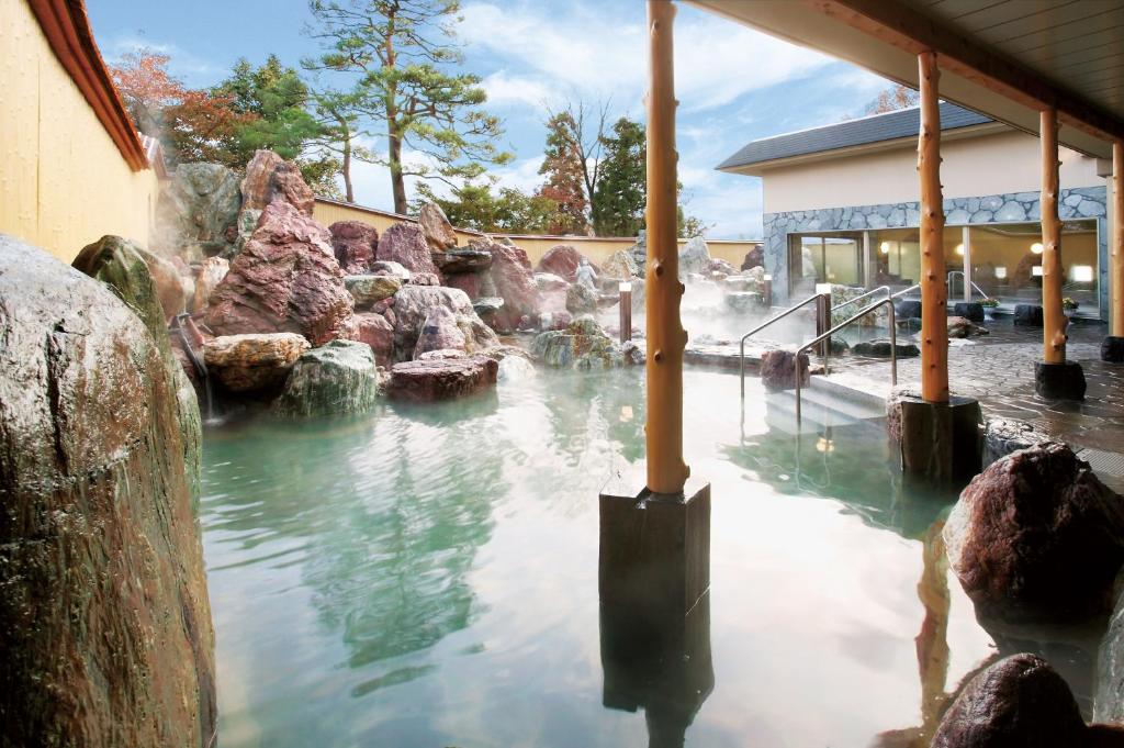 une piscine d'eau avec des rochers devant un bâtiment dans l'établissement Kintarou Onsen Hotel, à Uozu