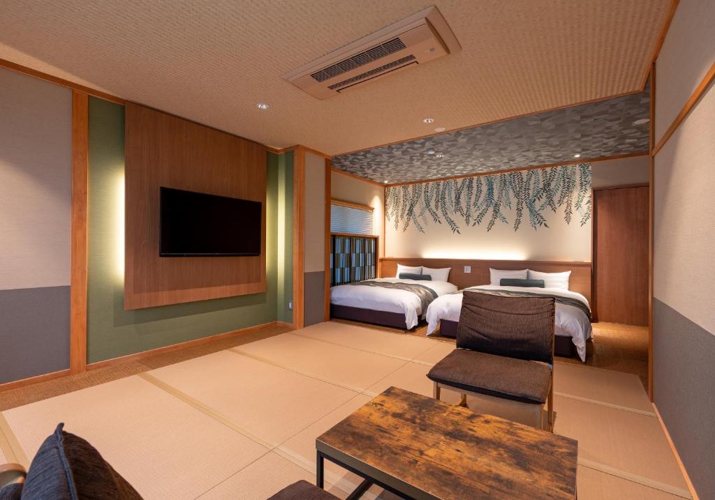 une chambre d'hôtel avec deux lits et une télévision dans l'établissement Oyado Sansui, à Achi 29 autres photos