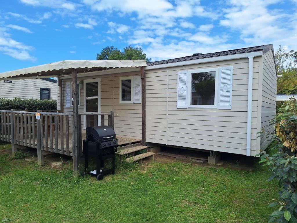une petite maison avec un barbecue dans la cour dans l'établissement Chez Cédric et Vivi mobil home 6 pers, à Argelès-sur-Mer