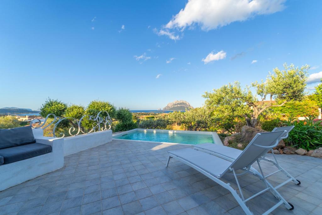 une terrasse avec une piscine et deux chaises dans l'établissement Sa Muda by DomusAway, à Porto San Paolo