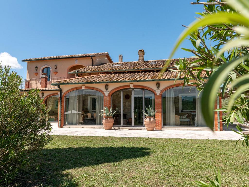 une maison avec de grandes fenêtres et des plantes dans la cour dans l'établissement Villa Le Cascate by Interhome, à Saturnia
