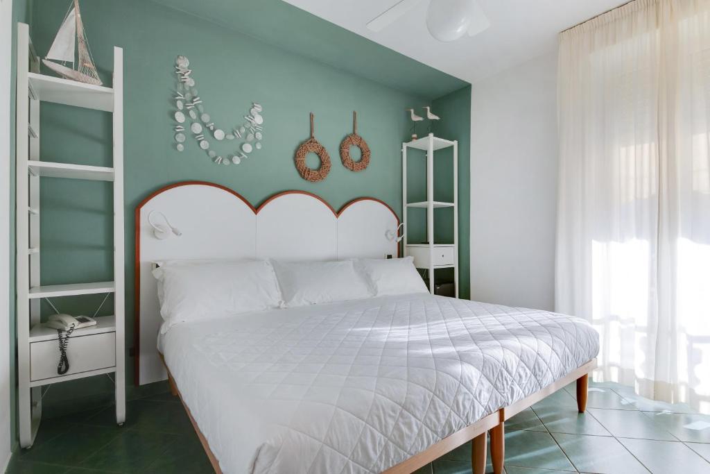 une chambre avec un lit blanc et un mur vert dans l'établissement Pinetina Mare Baby Family Hotel, à Cervia