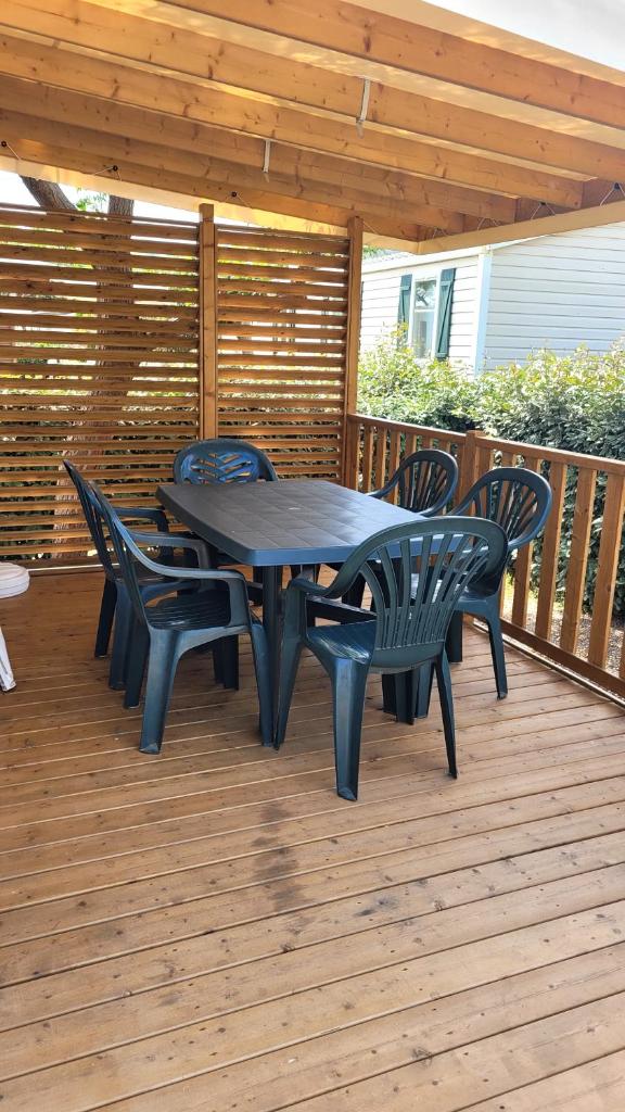 une table et des chaises noires sur une terrasse en bois dans l'établissement Mobilhome 6 personnes, à Vic-la-Gardiole