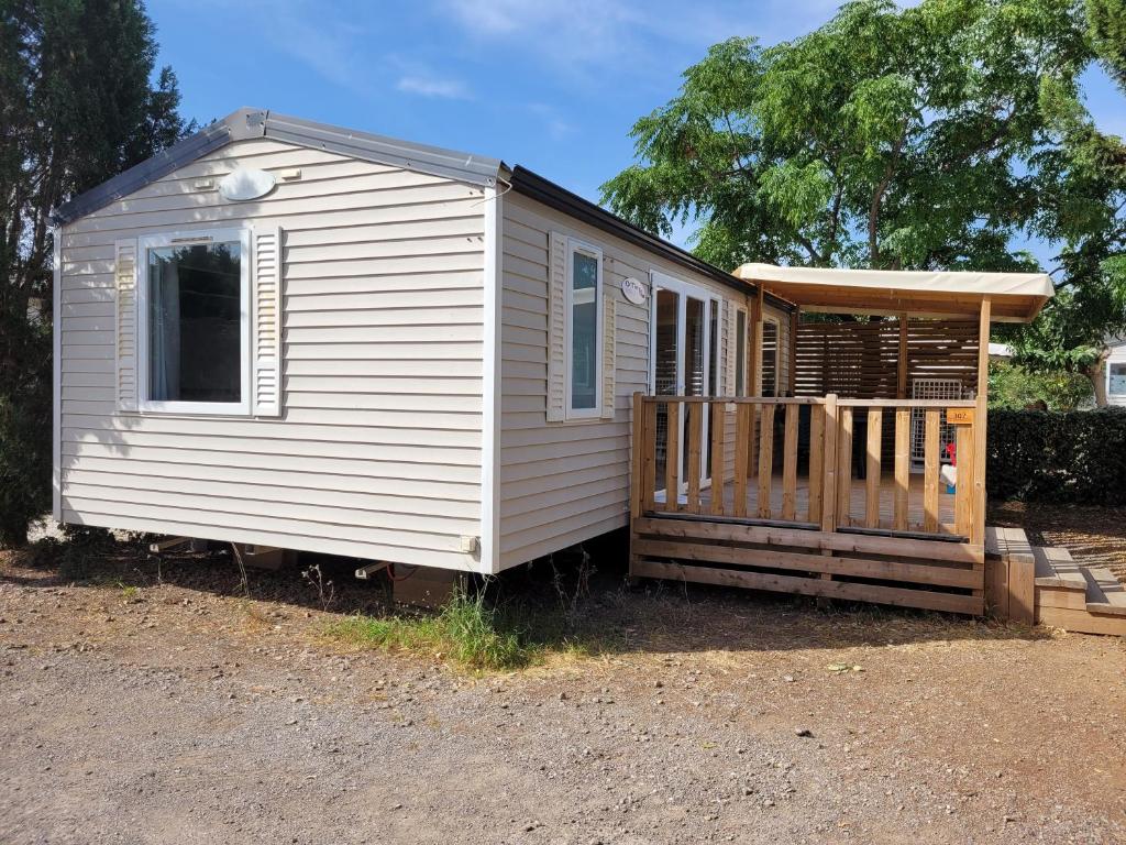 une petite maison blanche avec une terrasse couverte et une terrasse dans l'établissement Mobilhome 6 personnes, à Vic-la-Gardiole