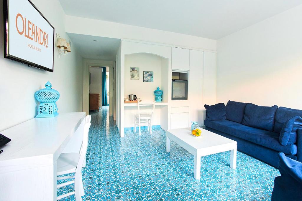 un salon avec un canapé bleu et une table dans l'établissement Oleandri Resort Paestum, à Paestum