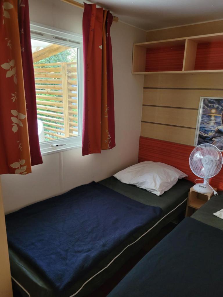 une petite chambre avec deux lits et une fenêtre dans l'établissement Bungalow cosy pour 6 personnes, à Ivry-la-Bataille