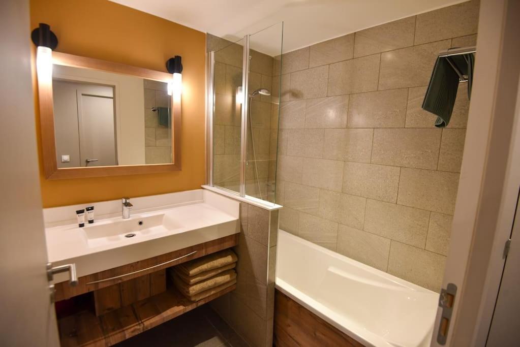 une salle de bain avec un lavabo, une baignoire et un miroir dans l'établissement Twin Peaks Lodge - Avoriaz, à Avoriaz