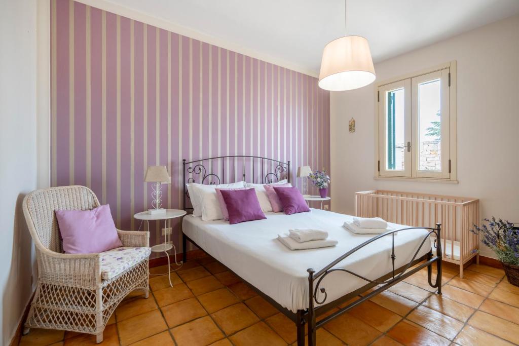 - une chambre avec un lit doté d'oreillers violets et d'une chaise dans l'établissement Villa Poggio Verde with pool - Exclusive Retreat, à Noicàttaro 33 autres photos